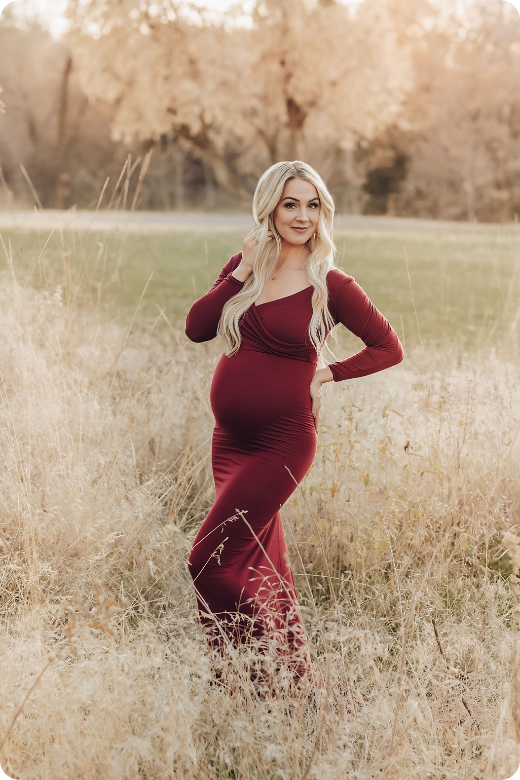mom in cranberry red maternity gown poses in Utah