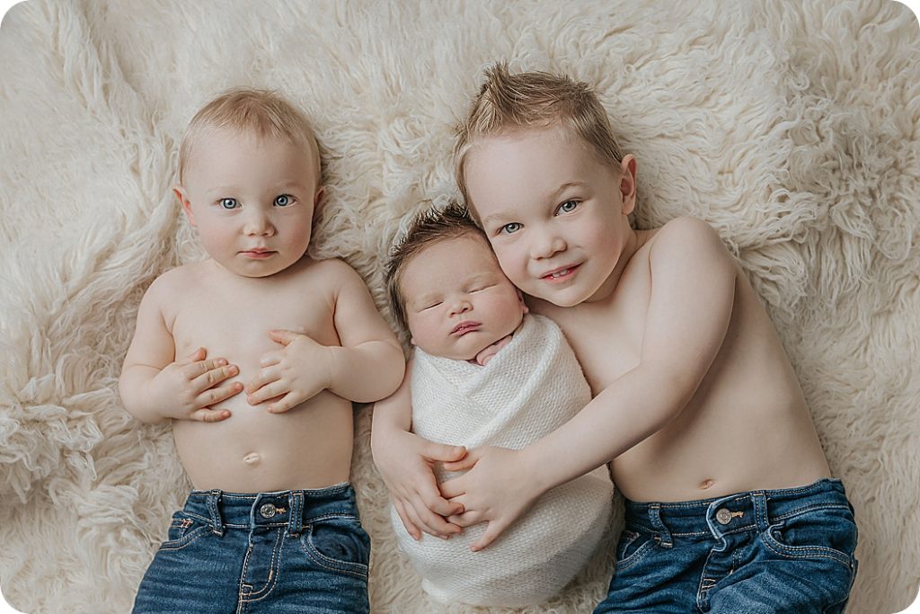 big brothers hold baby during classic newborn session