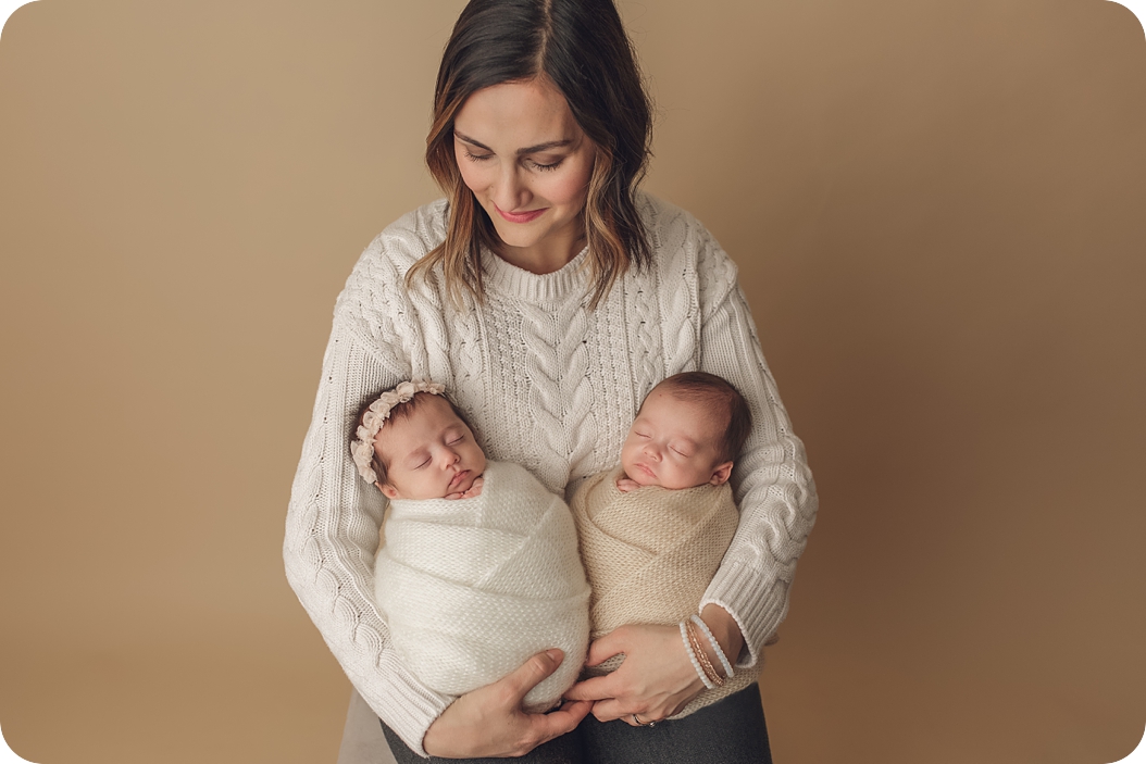 mom holds twin newborn babies during Utah newborn session with Beka Price Photography