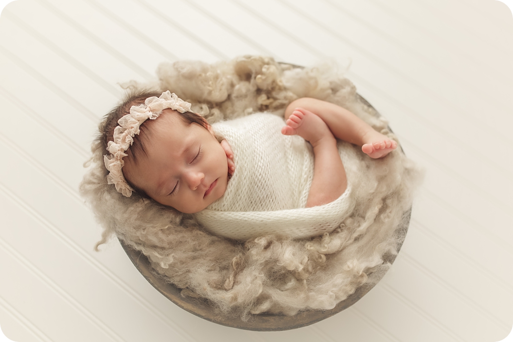 newborn baby girl sleeps in basket with fluffy ivory blanket photographed by Beka Price Photography