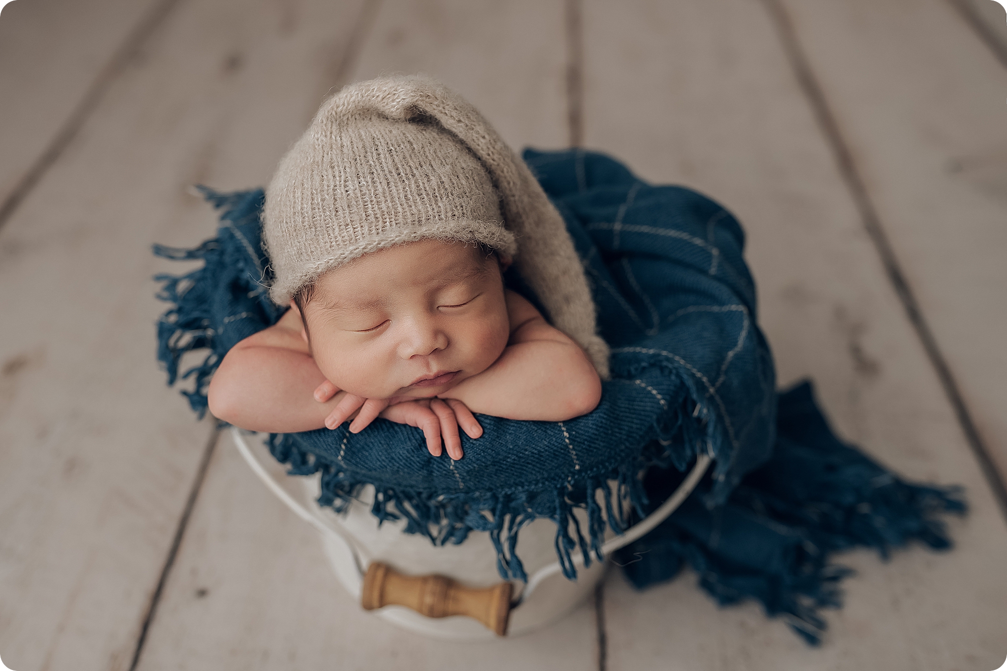 baby boy sleeps in basket on teal blanket during classic studio newborn session with Beka Price Photography