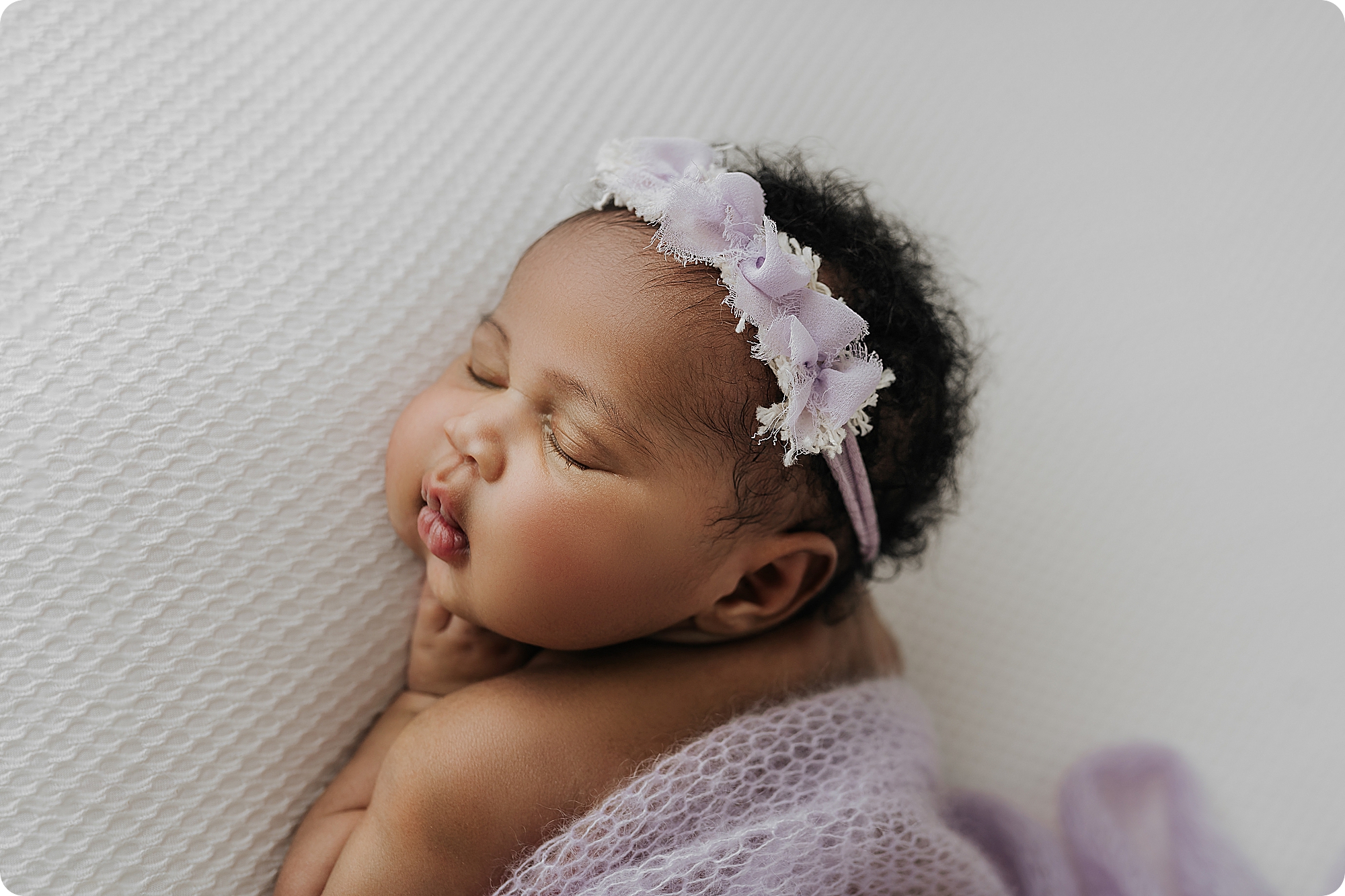 baby girl sleeps in pastel purple wrap with headband during session with Beka Price Photography