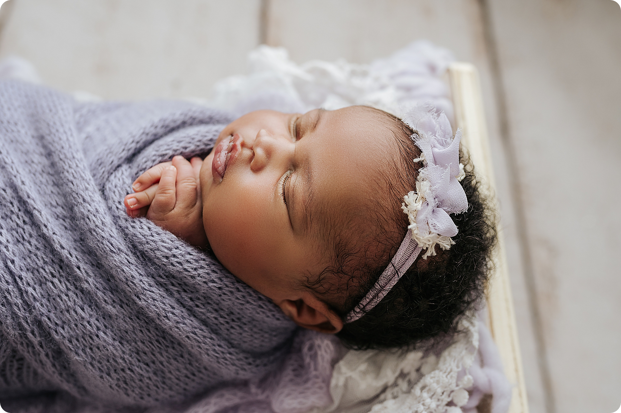 baby girl sleeps in purple wrap during Timeless Studio Newborn Portraits 