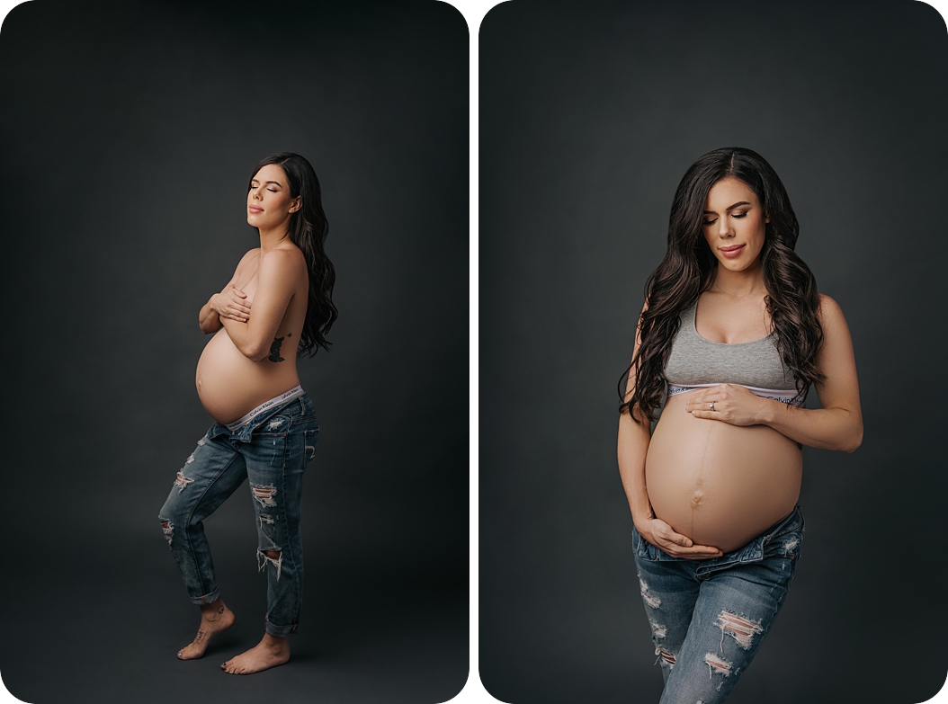 mom in jeans and bra holds belly during dramatic fashion studio maternity portraits in Utah