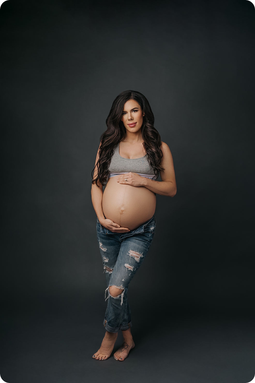 mom in Calvin Klein bra and jeans poses for Beka Price Photography during studio maternity photos in Utah