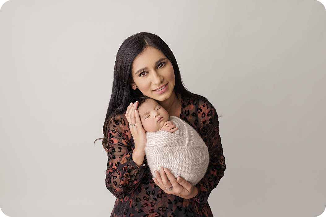 mom holds new baby boy in cream wrap during Utah newborn photos in studio 