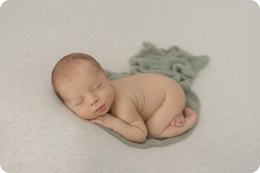 baby boy sleeps on sage green wrap during newborn photos in Utah studio