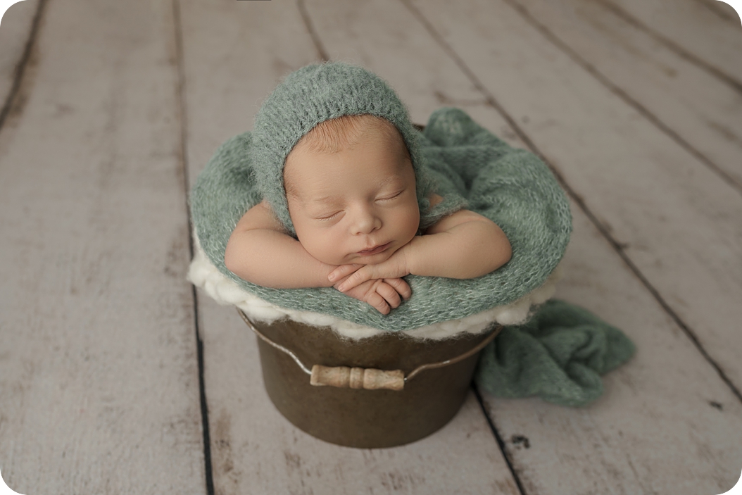 baby sleeps in pail during newborn session in Utah studio