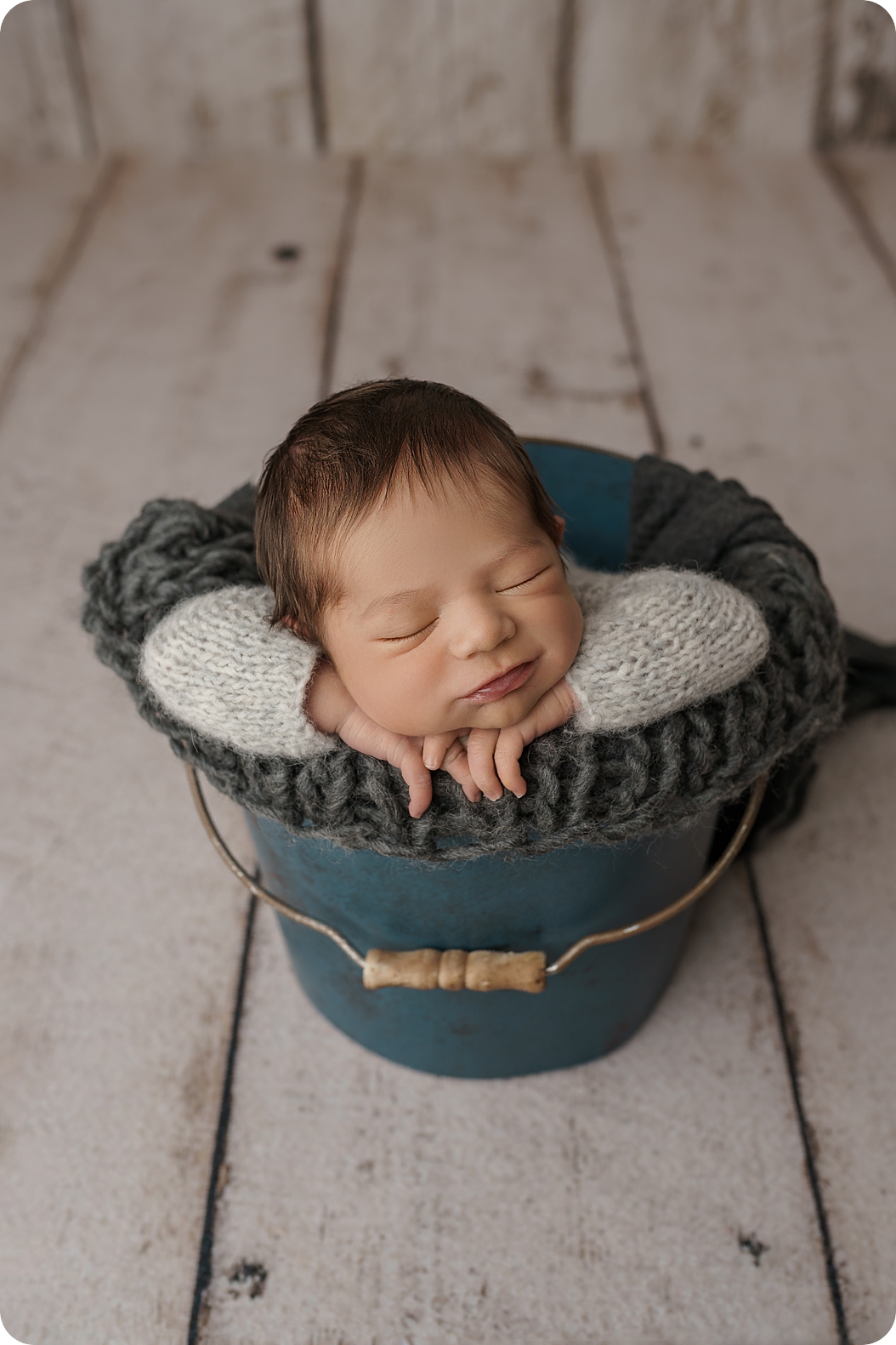baby sleeps in teal bucket with grey blanket during newborn photos with Beka Price Photography 