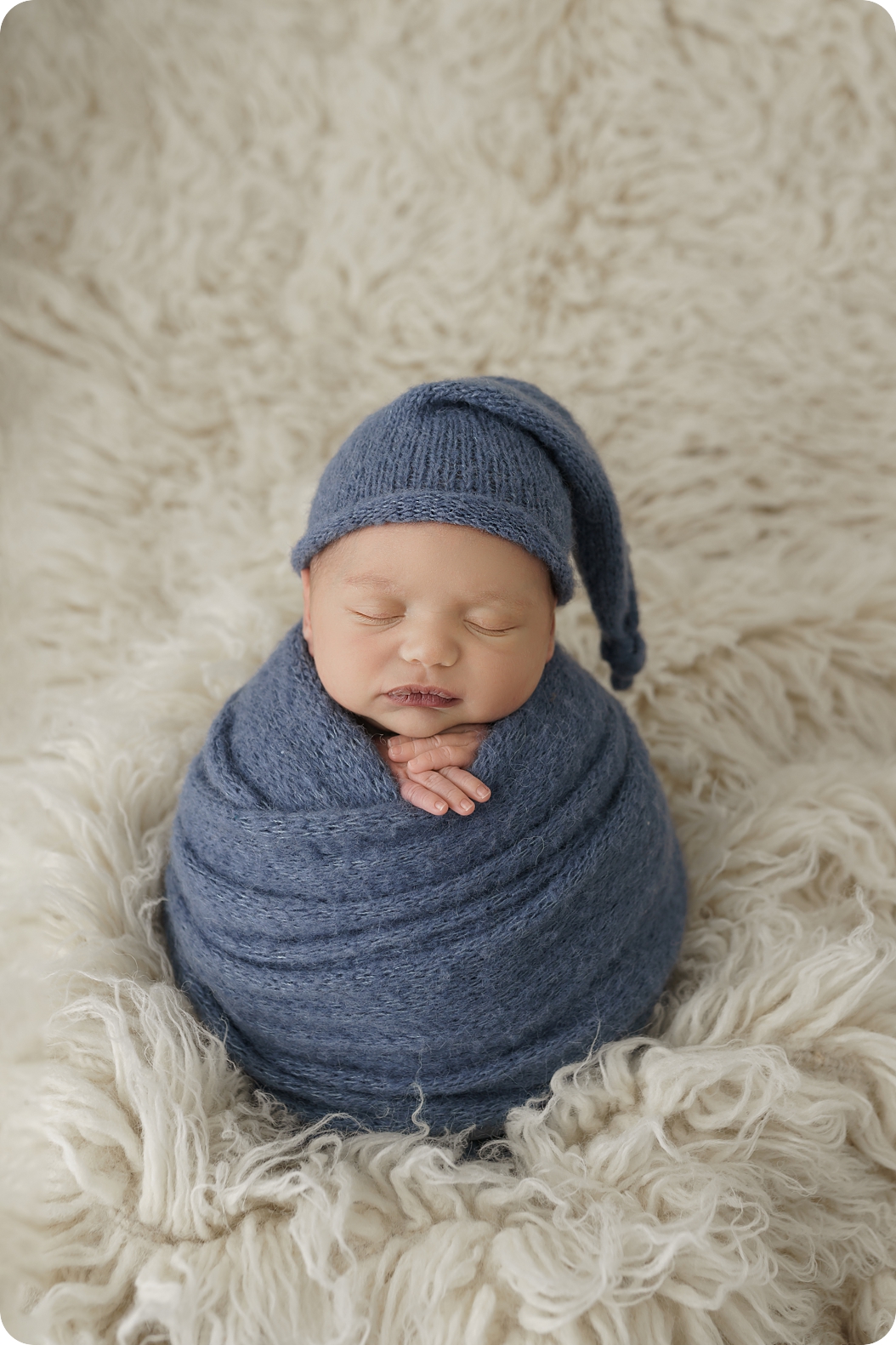 baby in blue wrap and blue knit cap sleeps during newborn photos with Beka Price Photography
