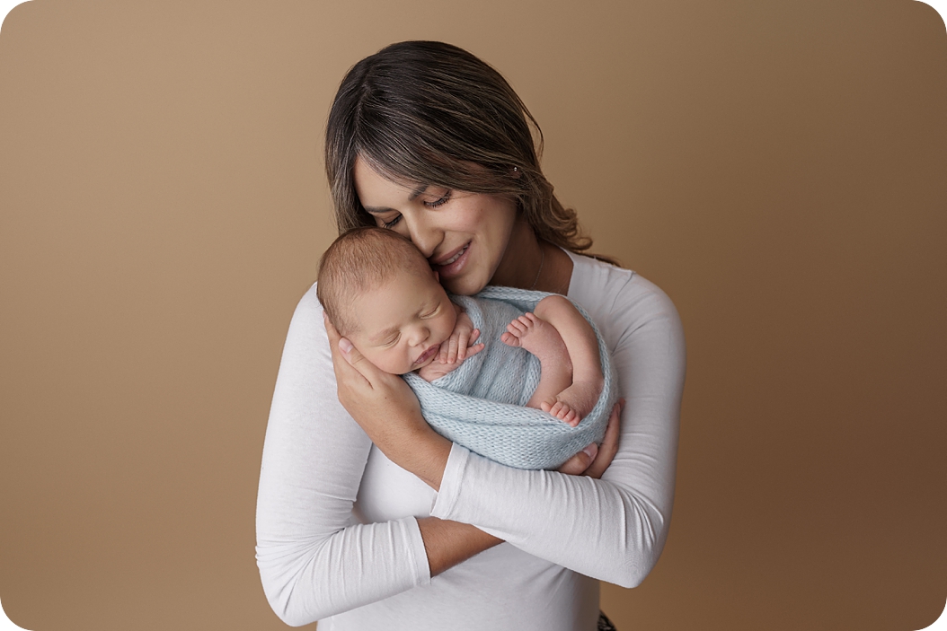 mom snuggles baby boy during newborn session in Utah