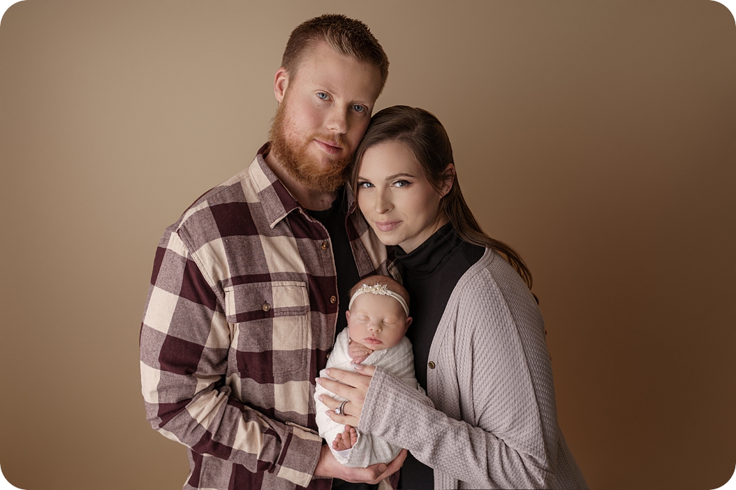 parents hold baby girl during newborn session with pastel purple accents