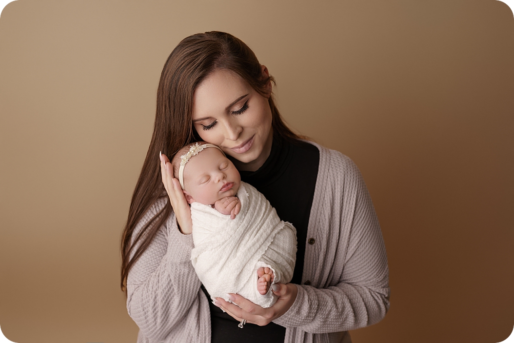 mom and baby girl snuggle during newborn session with pastel purple accents