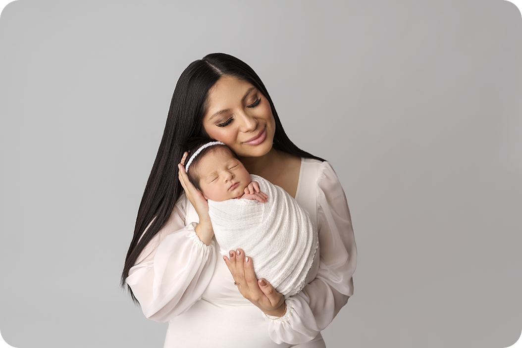 mom snuggles baby girl during timeless newborn portraits in Utah studio