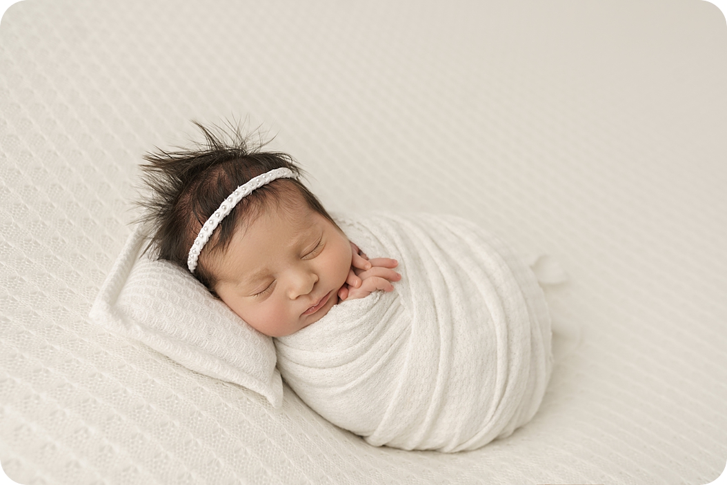 baby girl in ivory wrap sleeps during studio newborn session with Beka Price Photography 