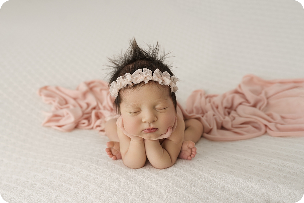 baby girl in froggy pose with pink floral crown sleeps during newborn photos with Beka Price Photography 