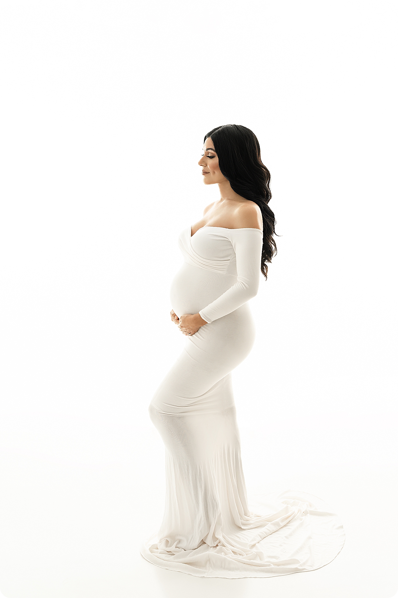 expecting mother in white gown poses in Utah studio