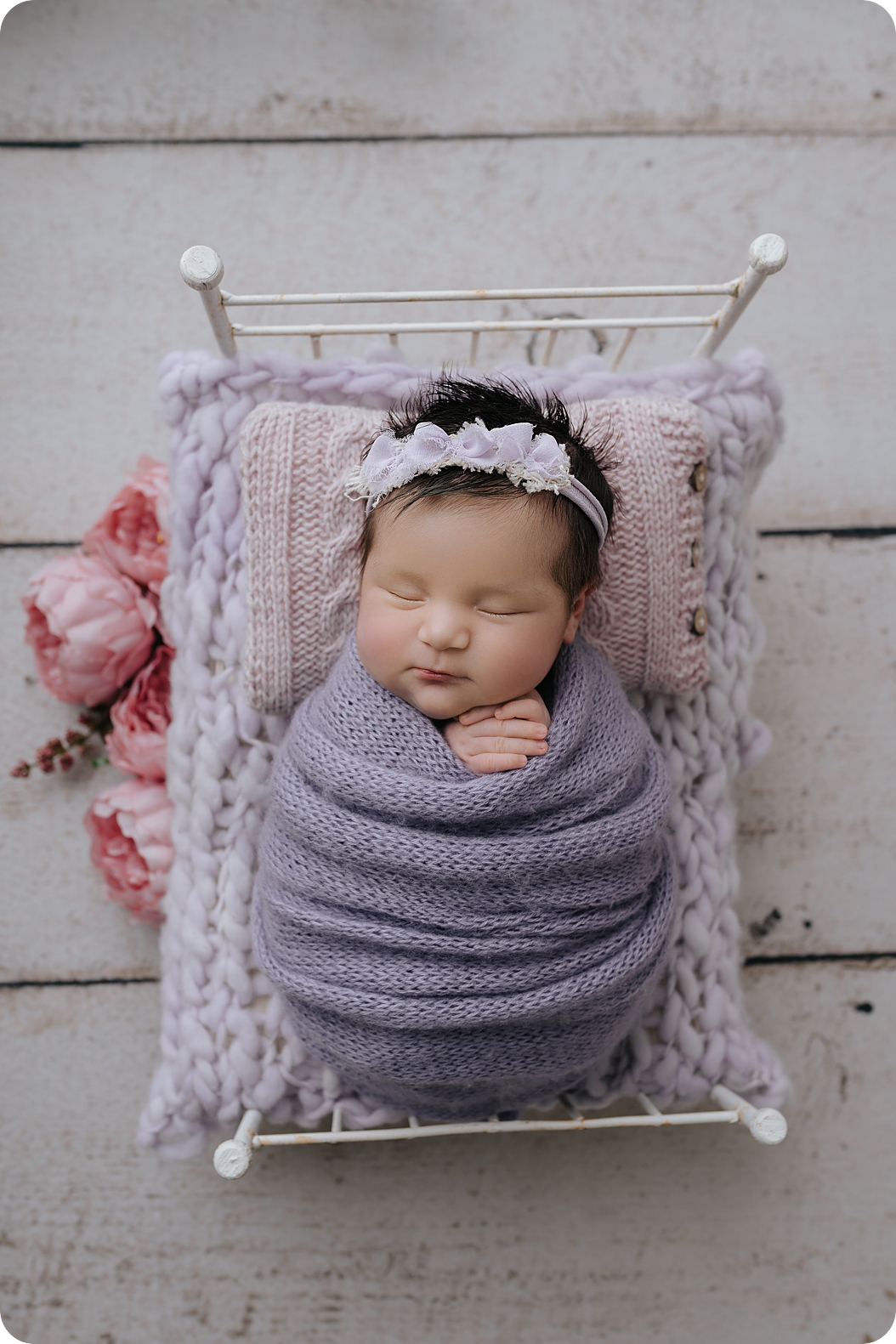 baby girl sleeps on bed with purple knit wrap