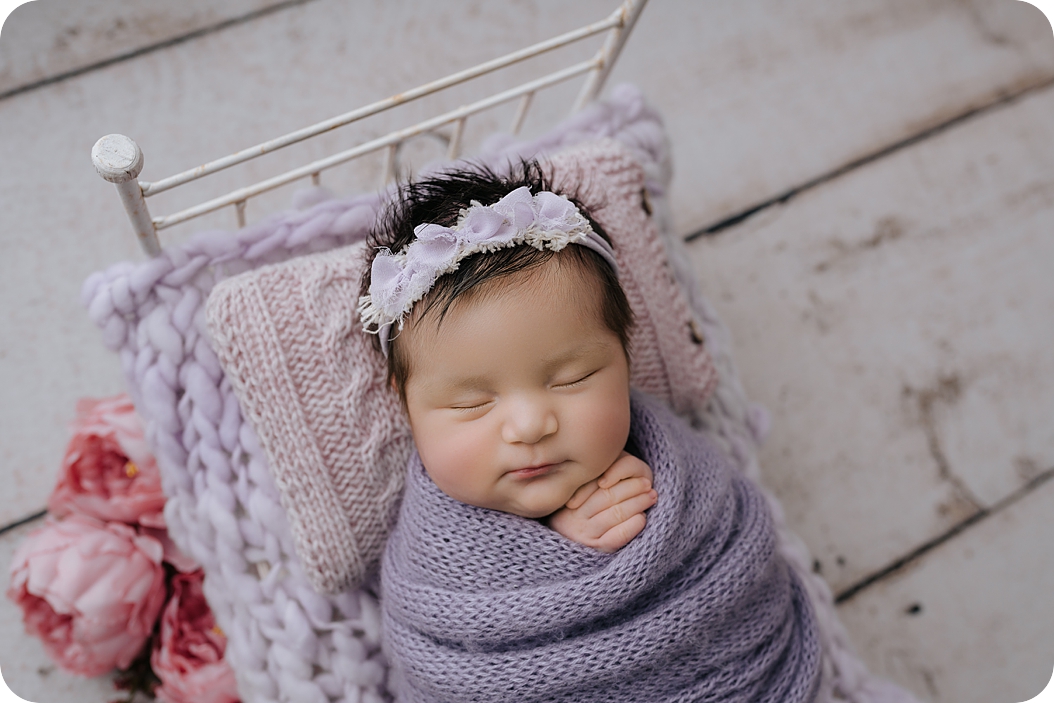 baby girl sleeps in purple wrap during Utah Newborn Session in Holladay Studio