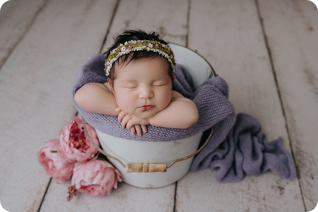 baby girl sleeps in white bucket during newborn photo session