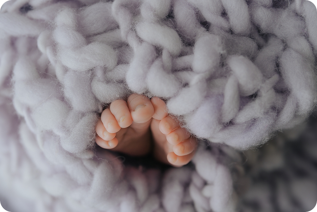 baby toes poke through lavender blanket 