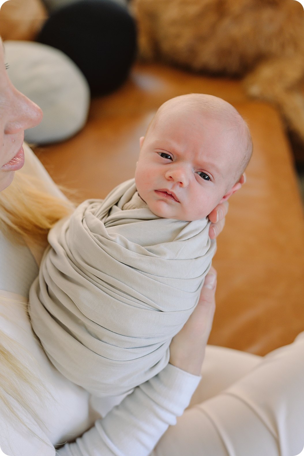 mom holds baby girl in tan swaddle during Lifestyle Newborn Session in Park City