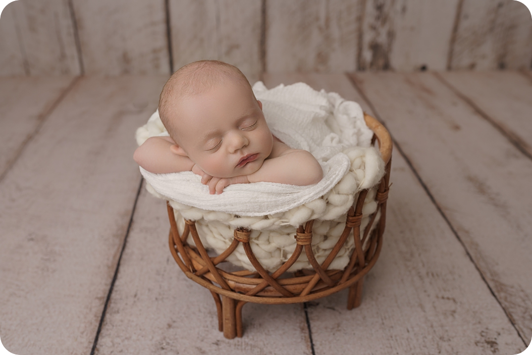 baby girl sleeps in basket during newborn portraits in studio 