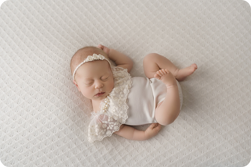 newborn baby girl sleeps on white blanket during spring studio newborn session