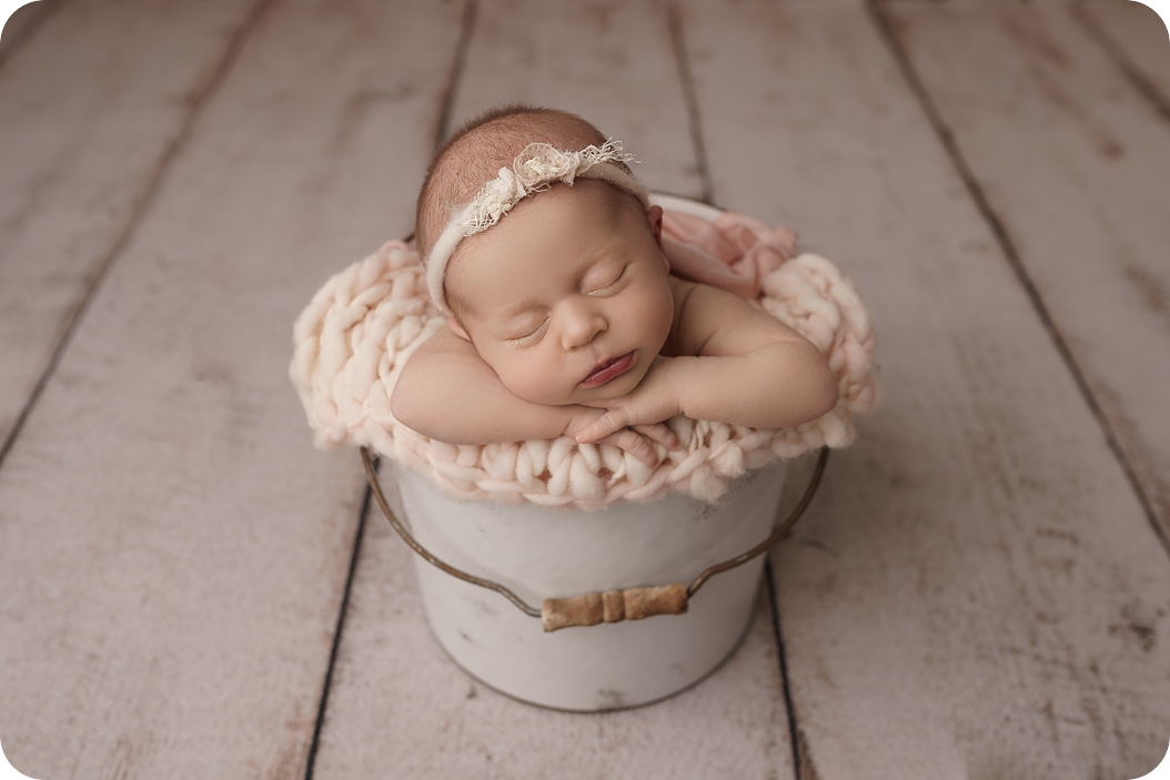 baby sleeps in pail during spring studio newborn session