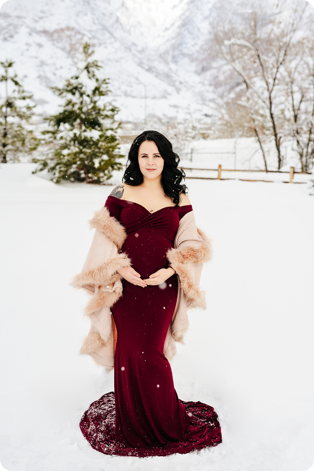 winter maternity portraits in the snow with mother in cranberry gown 