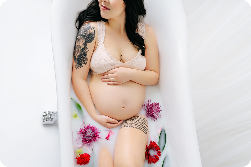 mother holds belly during milk bath in Utah studio maternity portraits