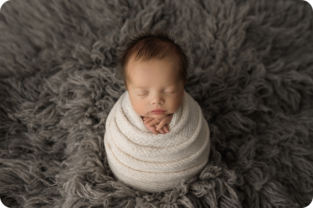 baby sleeps in white knit wrap during classic newborn portraits in studio