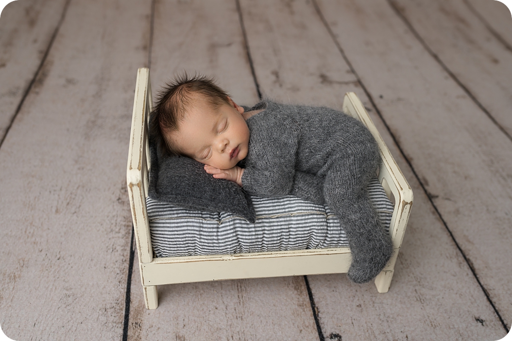 baby sleeps on small bed during classic newborn portraits in studio