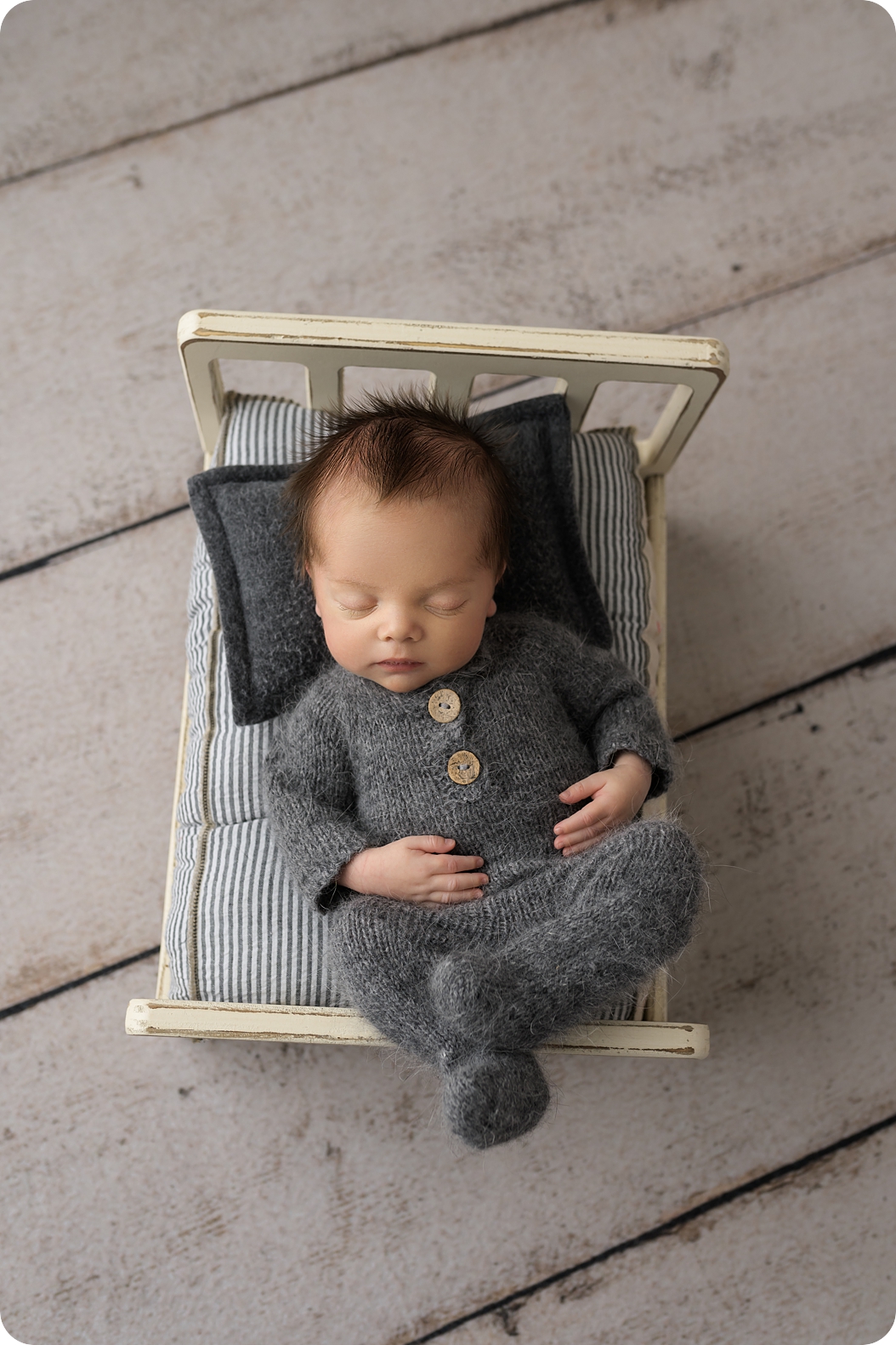 baby sleeps in grey sweater during classic newborn portraits in studio