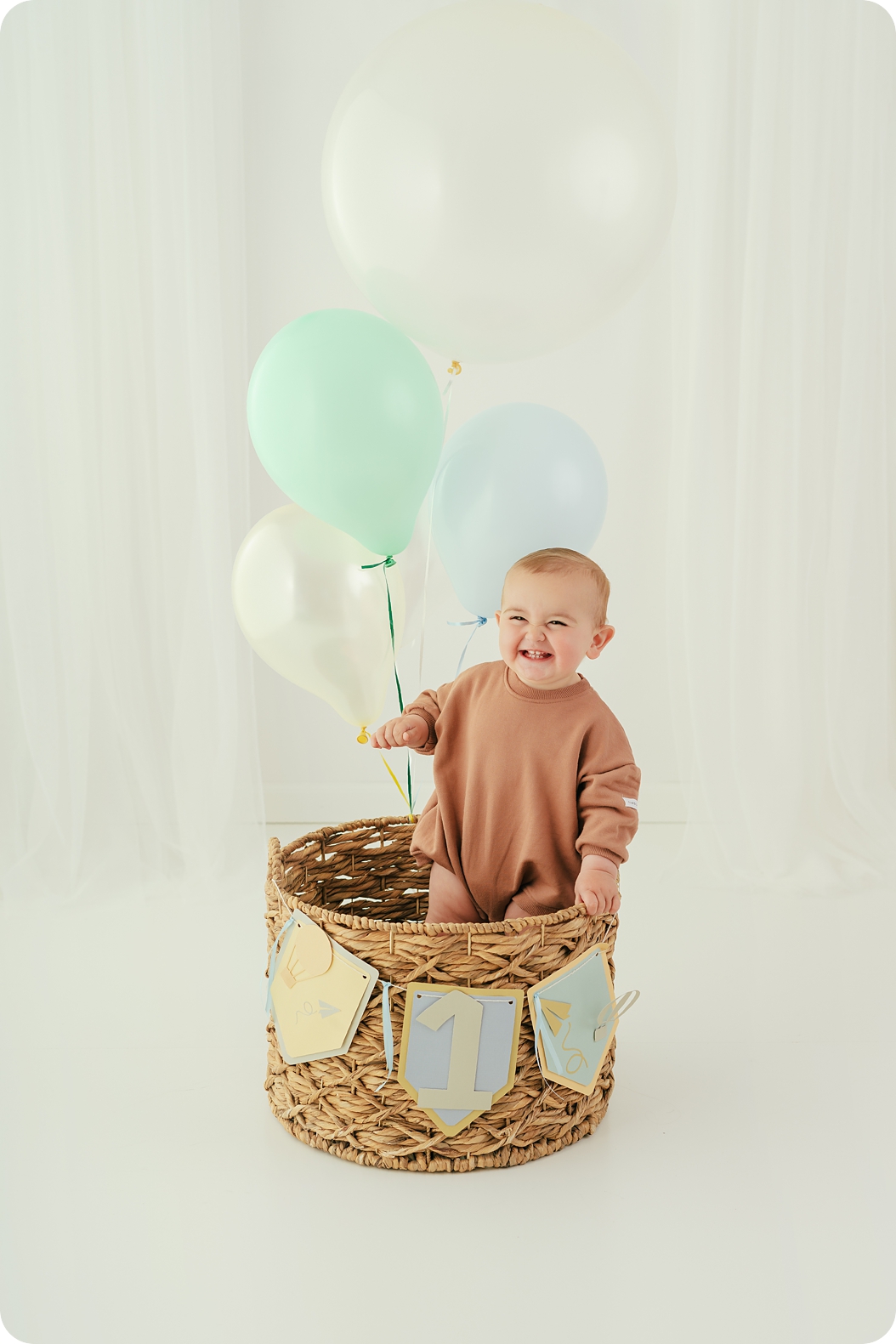 one year old smiles playing with balloons during timeless first birthday portraits