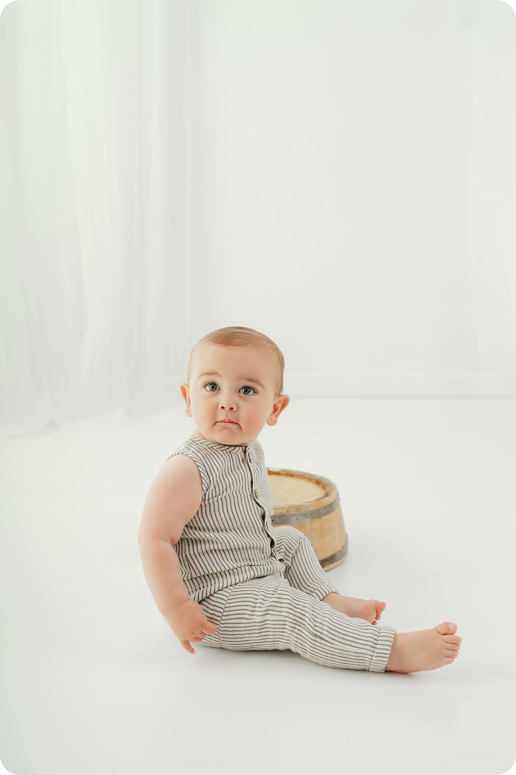 baby sits on studio floor during timeless first birthday portraits