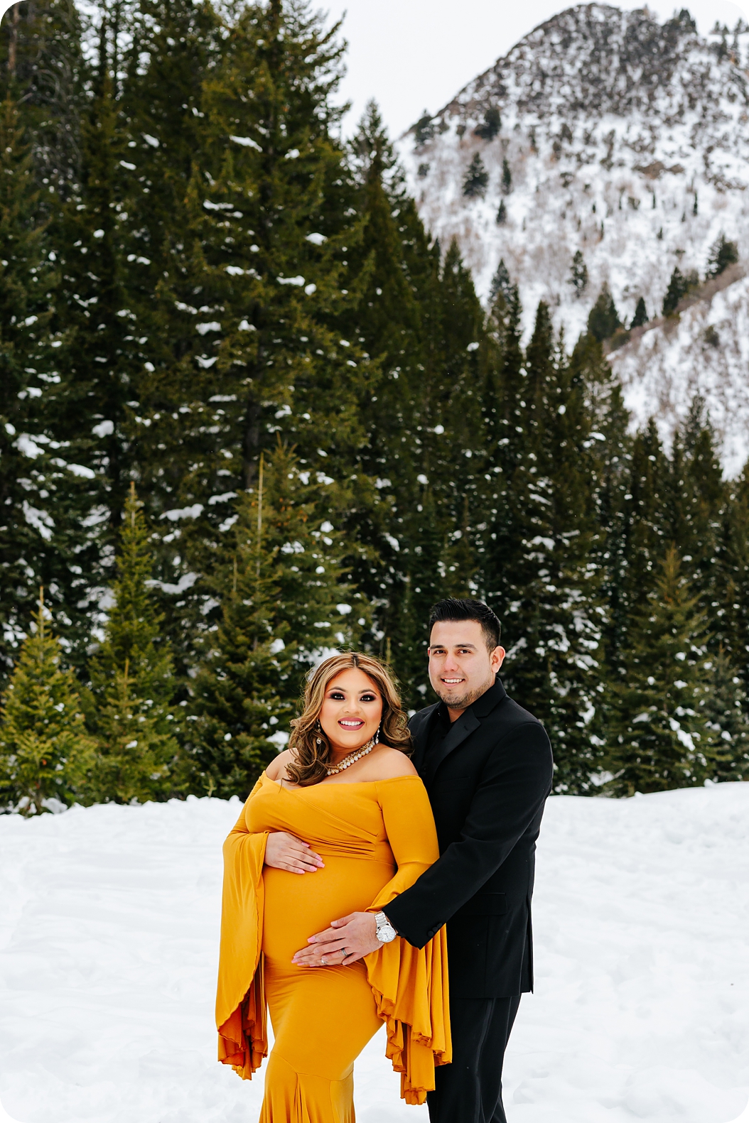 expecting parents pose in snow during Utah maternity portrait session