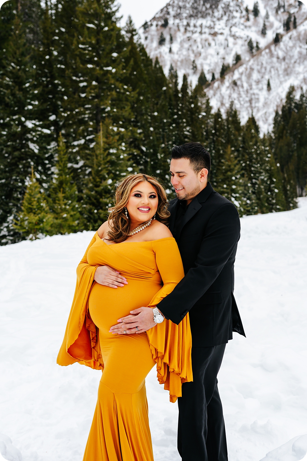 parents hold mom's belly in the snow during Utah maternity photos