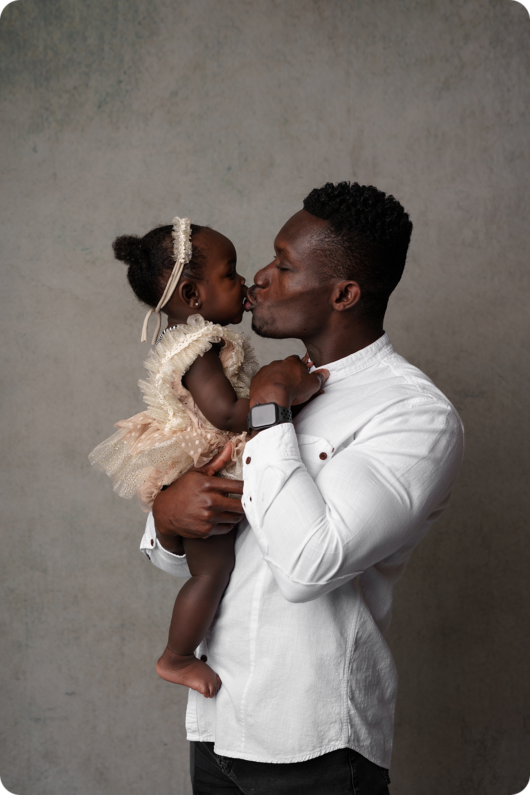 dad and toddler kiss during classic family portraits in studio 