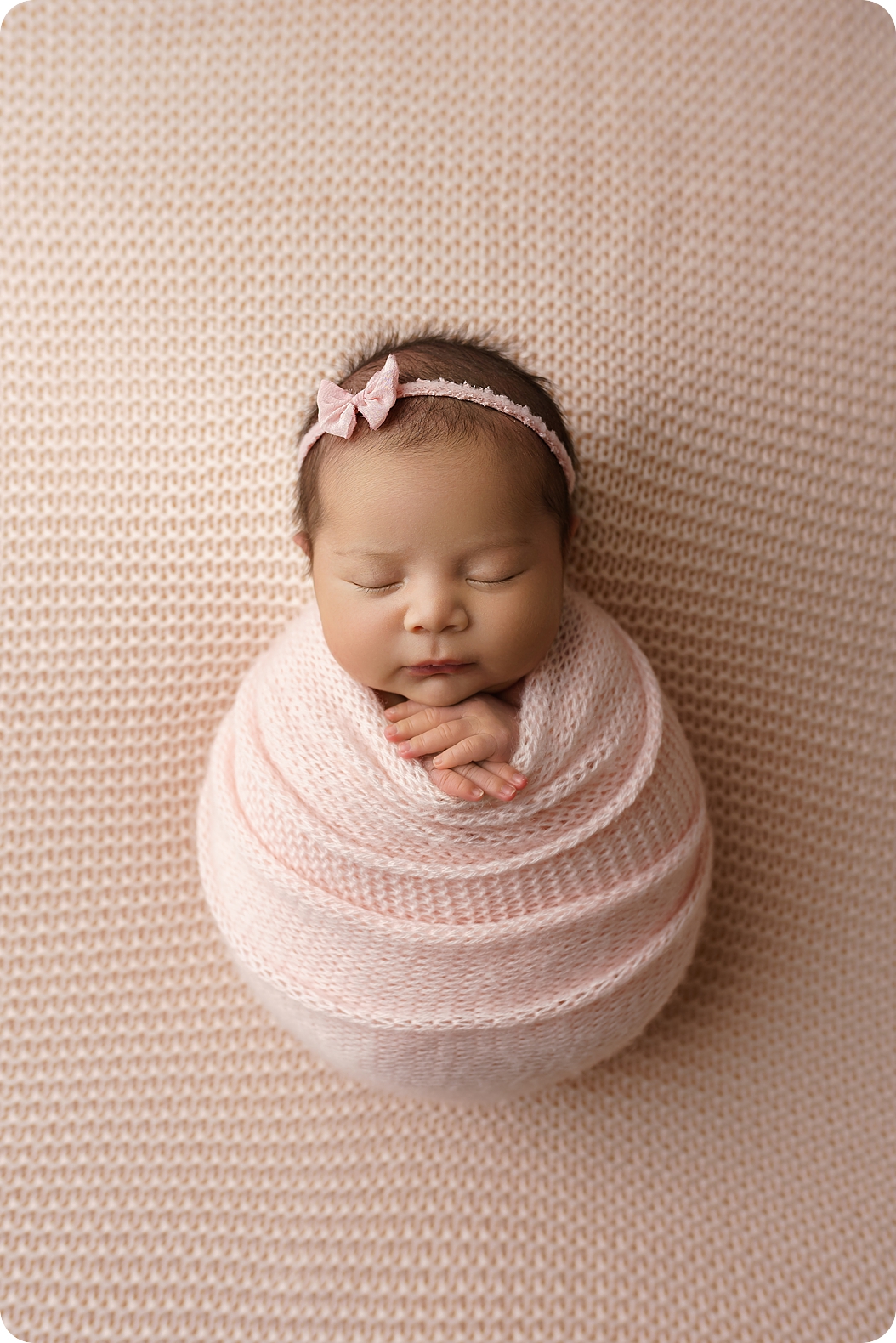 baby girl in pink wrap sleeps during studio newborn session in Utah 