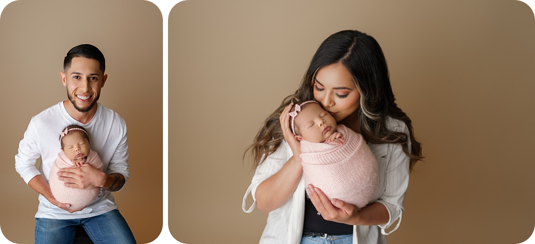 parents hold baby girl in pink wrap during pastel newborn portraits  in Utah studio