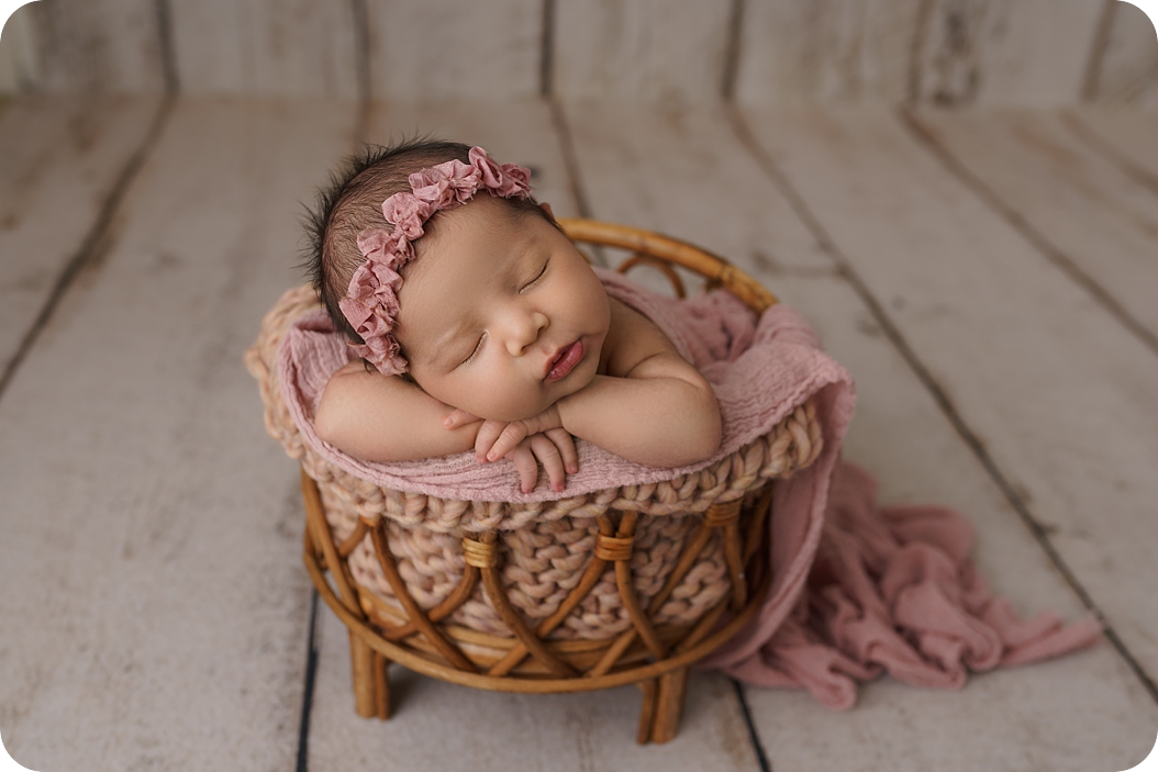 baby sleeps in basket in pink wrap during pastel newborn portraits 