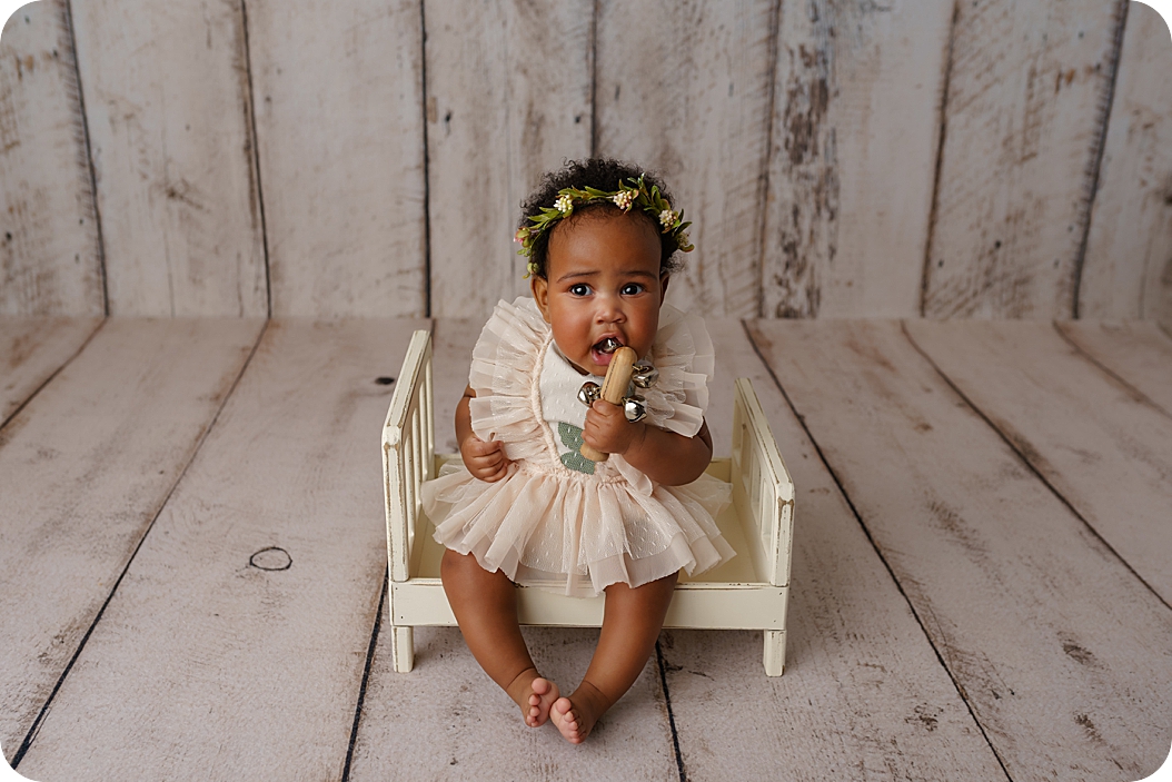 baby chews on wooden toy during milestone photos in Utah studio 