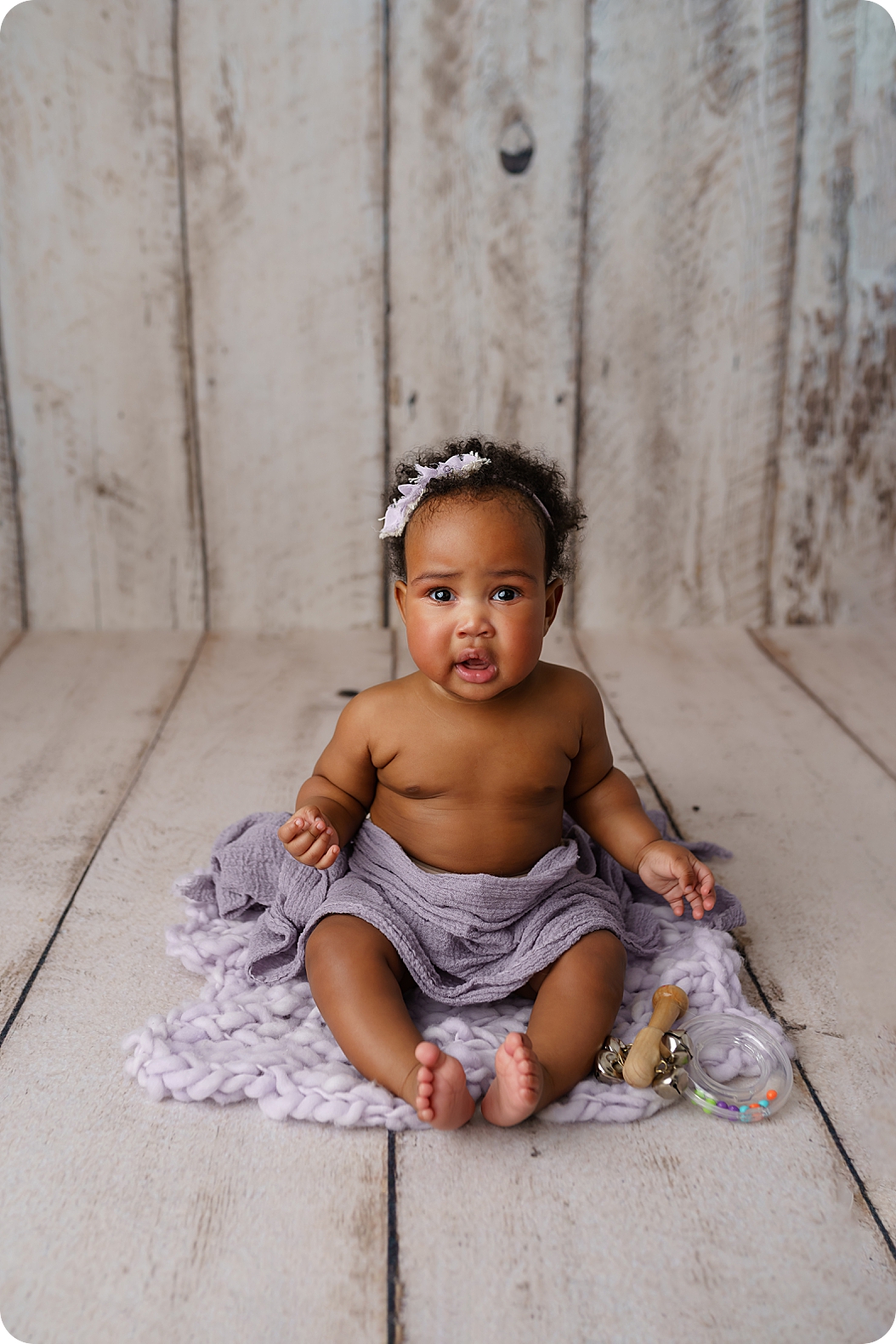 baby girl sits in purple wrap with toys during milestone photos in Utah studio