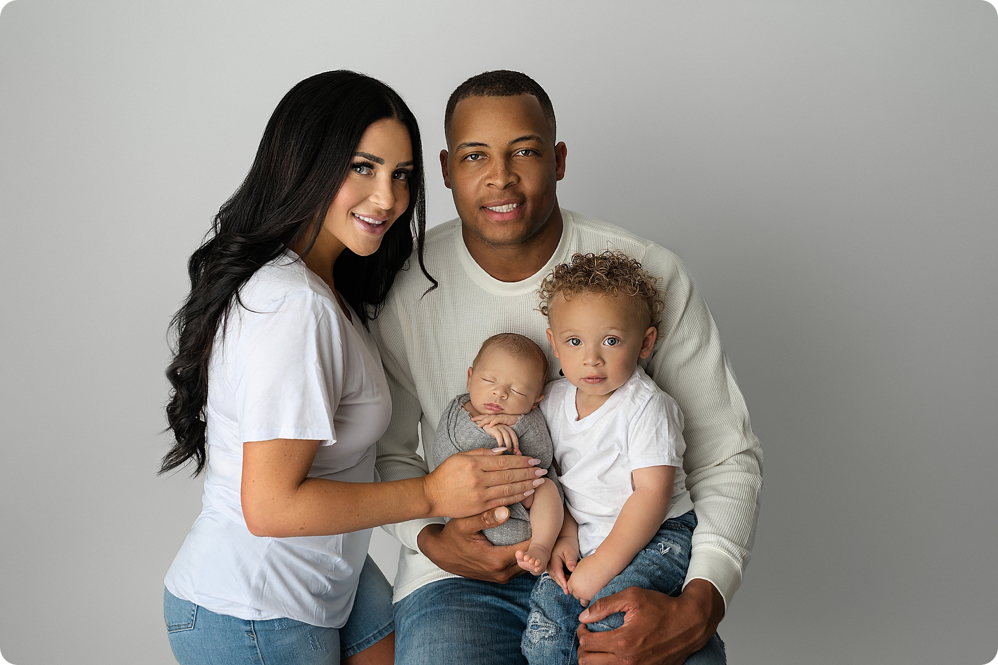 family sits together during newborn photos in Utah studio