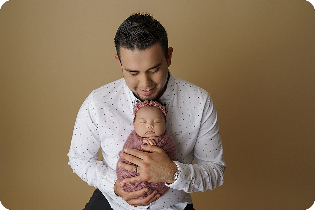 dad holds baby girl during newborn photos in Utah studio