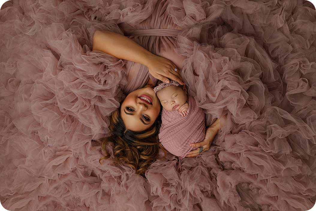 mom lays on pink rug with baby girl