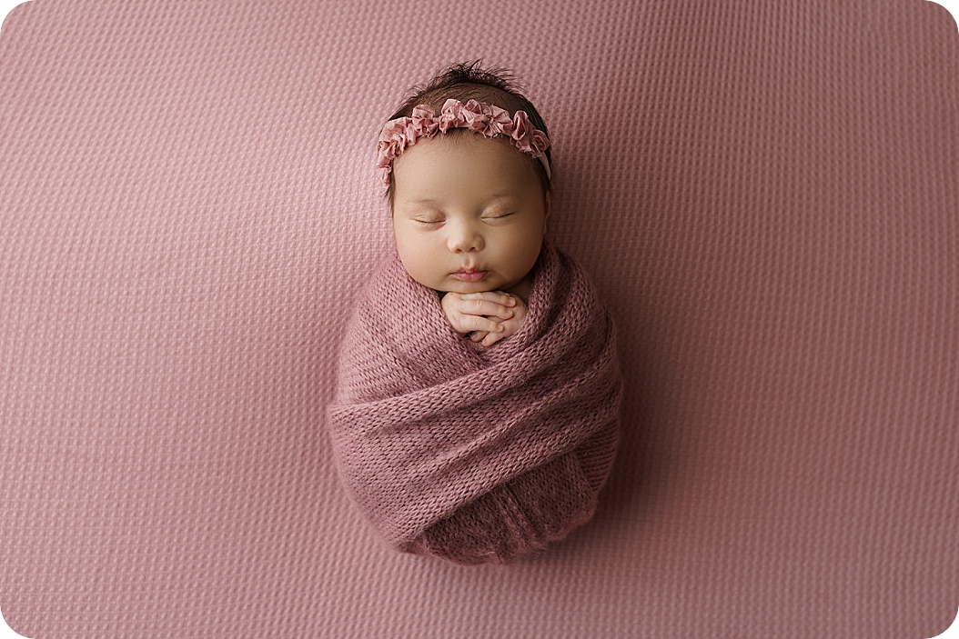 baby girl wrapped in mauve wrap sleeps during newborn photos
