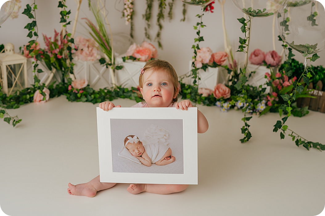 baby holds photo of newborn session in studio 
