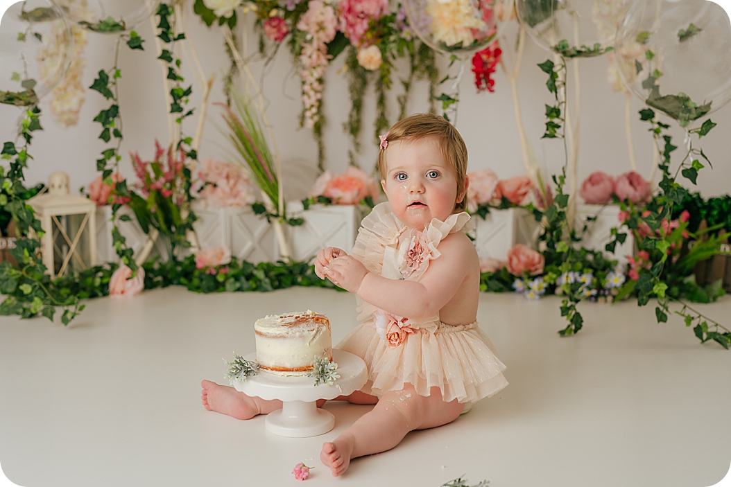one year old plays with icing during enchanted forest cake smash in Utah studio
